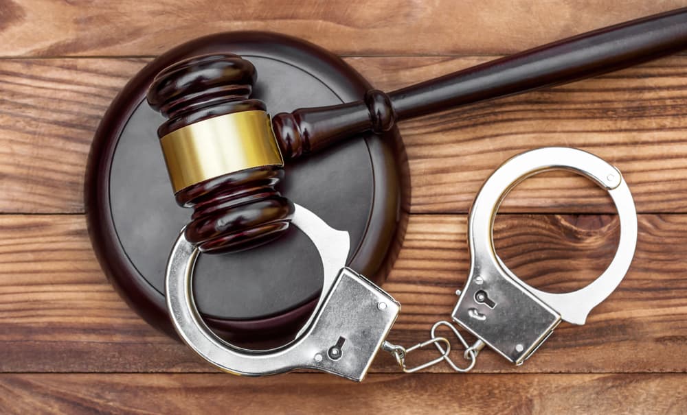 Gavel with stand and handcuffs on a wooden background, top view.