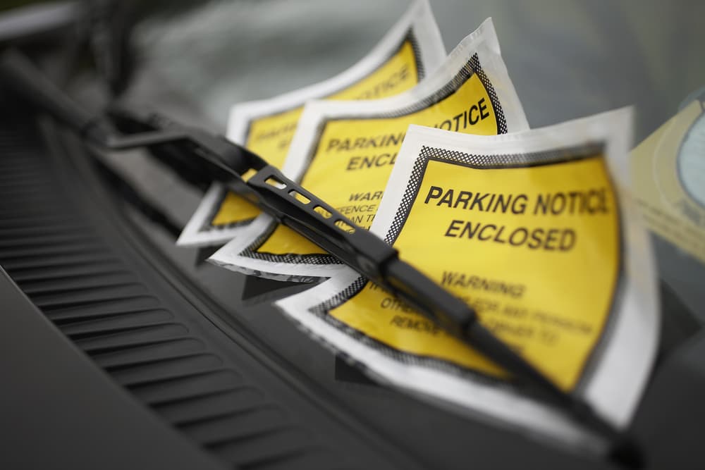 Close-up of a parking ticket placed under the windshield wiper of a car.






