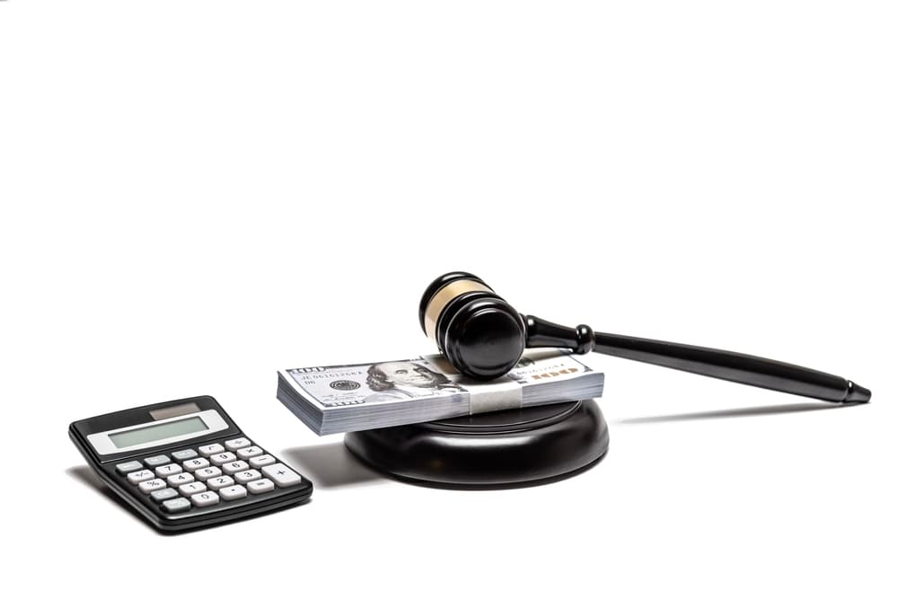 A legal gavel, currency with a calculator, depicting monetary fines and higher insurance rates